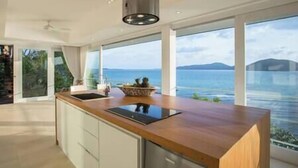 A modern kitchen with a wooden countertop, a built-in sink, and a view of the sea. - Element of 8 at Cape Laem Sor Estate by Elite Havens (Surat Thani)