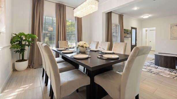 A dining area with a rectangular table set for six, surrounded by six chairs, with a chandelier above. - Two Kings, Heated Pool, Whirlpool Jet Bathtub &BBQ (Flower Mound)
