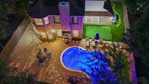 A two-story house with a backyard featuring a swimming pool, a patio with outdoor furniture, and a well-maintained lawn. - Two Kings, Heated Pool, Whirlpool Jet Bathtub &BBQ (Flower Mound)