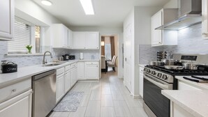 A modern kitchen with white cabinetry, stainless steel appliances, and a tiled backsplash. - Two Kings, Heated Pool, Whirlpool Jet Bathtub &BBQ (Flower Mound)