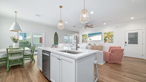 Una cocina moderna con muebles blancos, una isla central con pileta e iluminación colgante.