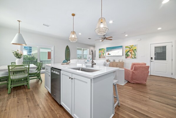 A modern kitchen with white cabinetry, a central island with a sink, and pendant lighting.