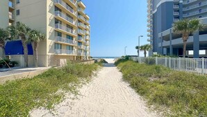 Un sendero que conduce a una playa, con un edificio Whaler a la izquierda y otro edificio a la derecha.