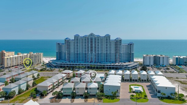 Un hotel grande con varios pisos y un patio central, situado cerca de una playa.