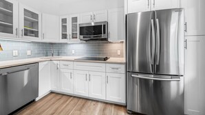 A modern kitchen with white cabinets, a stainless steel refrigerator, and a microwave.