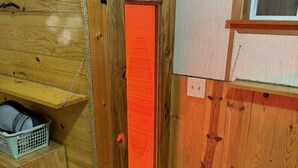 A wooden door with a red frame, a small shelf with a basket, and a wooden chair. - Charming 2-bedroom house in beautiful Republic with infrared sauna. (Republic)