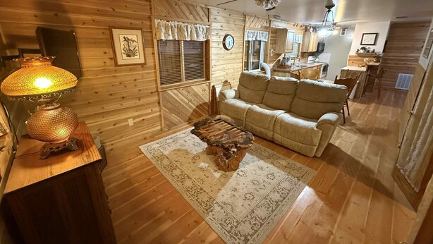 A cozy living room with a sofa, a coffee table, and a lamp. There is a dining area in the background with a table and chairs. - Charming 2-bedroom house in beautiful Republic with infrared sauna. (Republic)