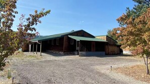 A wooden barn with a green roof, gravel driveway, and trees with autumn leaves. - Charming 2-bedroom house in beautiful Republic with infrared sauna. (Republic)