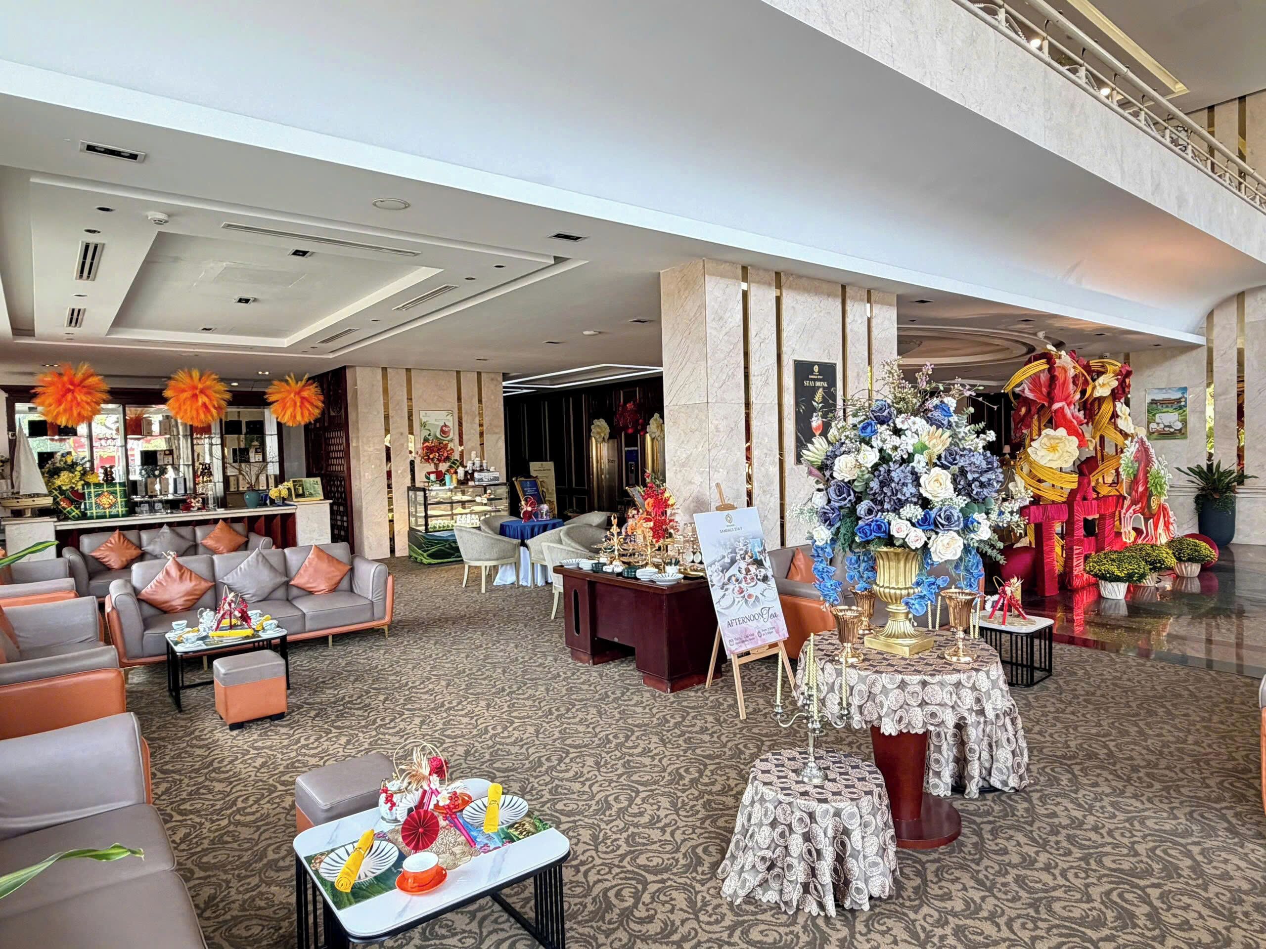 Un vestíbulo espacioso con una zona de estar, una mesa de recepción y una decoración floral.