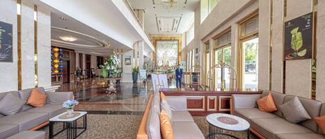 A spacious lobby with a grand chandelier, seating areas, and a reception desk.