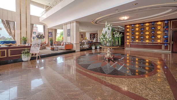 A spacious lobby with a polished marble floor, a reception desk, seating areas, and a decorative fountain. - Sandals Stay Hotel (Da Nang)