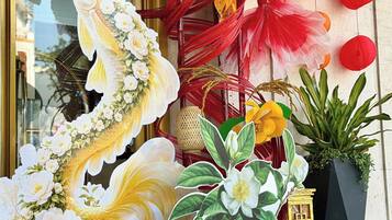 Fachada con grandes decoraciones florales, incluyendo una llamativa escultura de pez, y farolillos de papel rojo y amarillo.