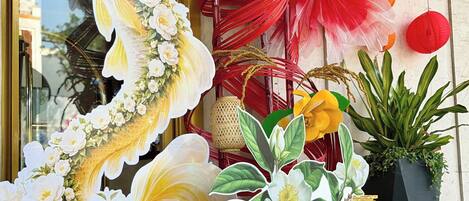 A storefront with large floral decorations, including a prominent fish sculpture, and red and yellow paper lanterns.