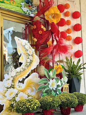 A storefront with large floral decorations, including a prominent fish sculpture, and red and yellow paper lanterns. - Sandals Stay Hotel (Da Nang)
