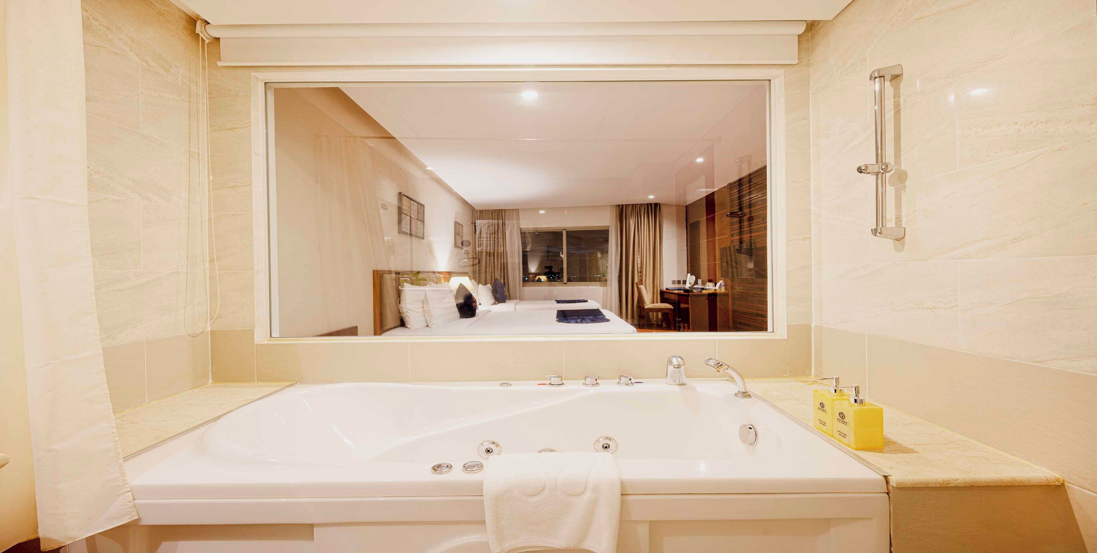 A modern bathroom with a large bathtub, a mirror, and a sink.