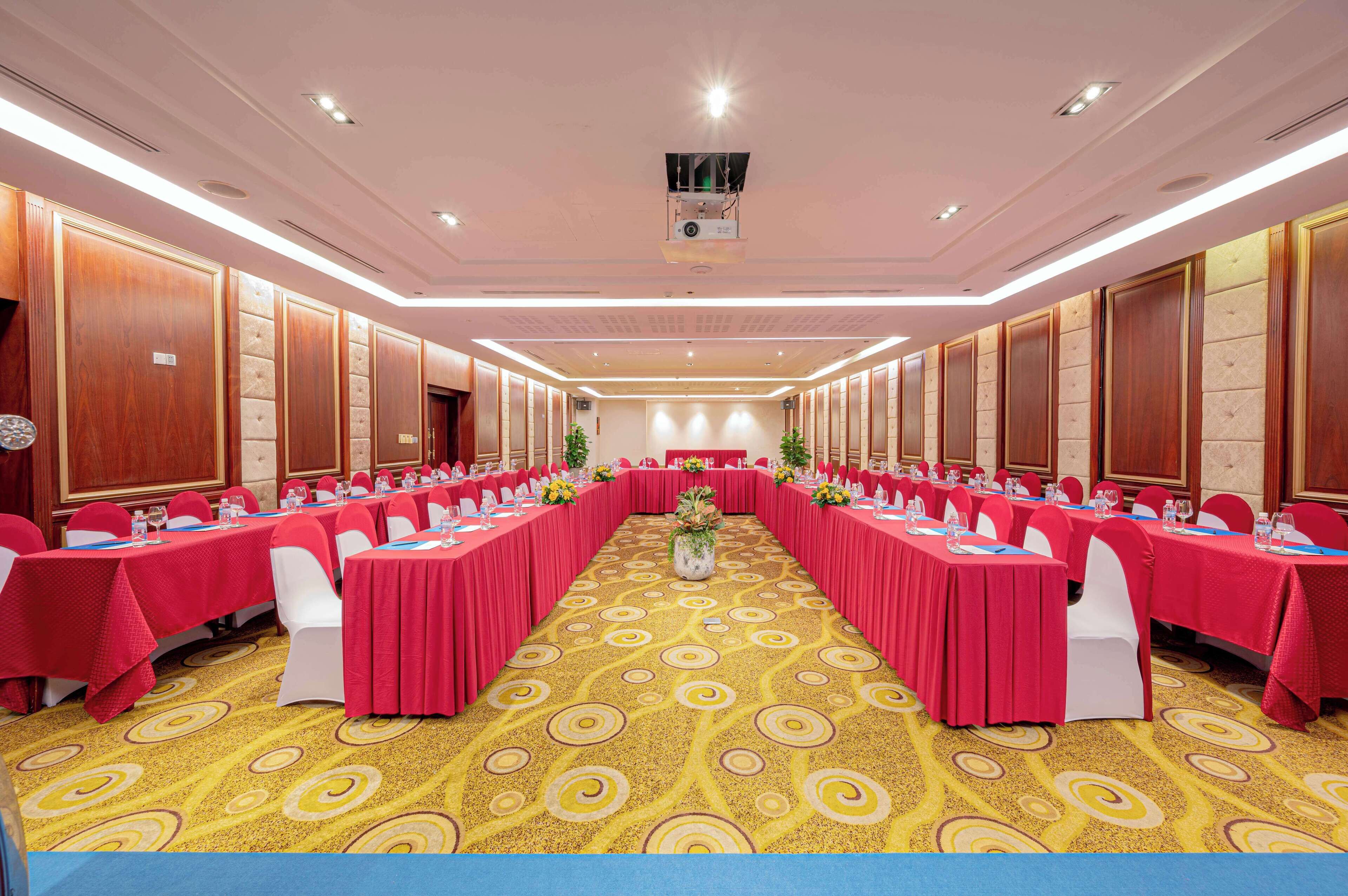 A conference room with long tables, red tablecloths, and white chairs.