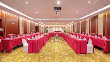 A conference room with long tables, red tablecloths, and white chairs.