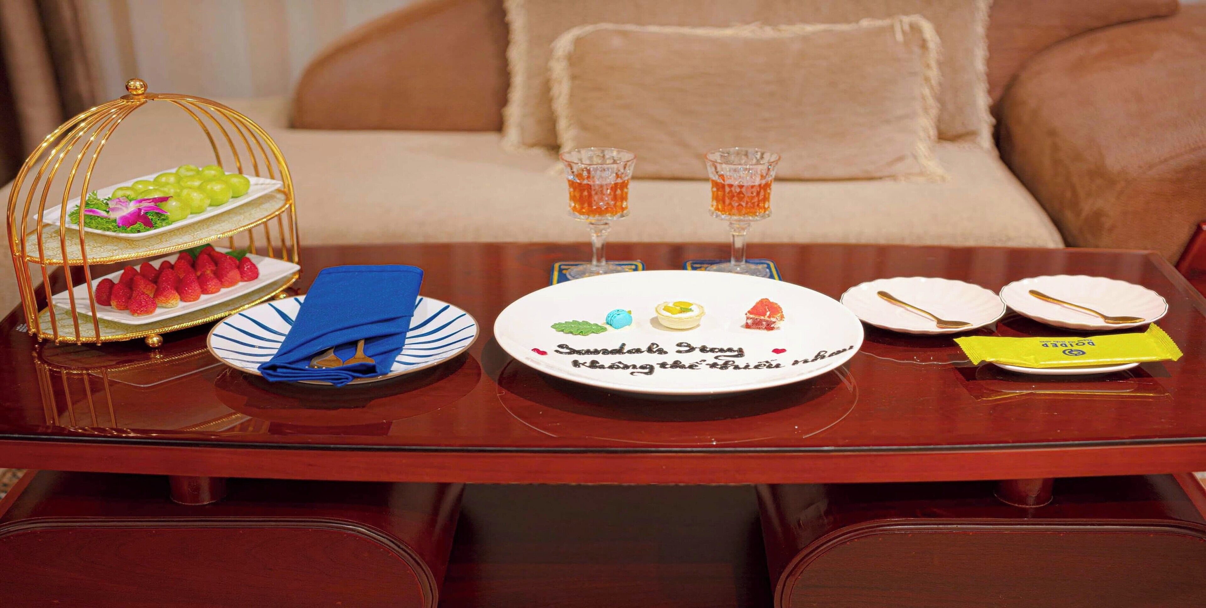 A dining table with a dessert tray, plates, cutlery, and glasses.