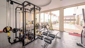 A gym with weightlifting equipment, a pool, and large windows. - Sandals Stay Hotel (Da Nang)
