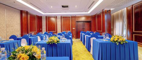 A conference room with rows of tables, blue tablecloths, and yellow carpeting.