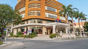 A tall, curved hotel with multiple floors, a prominent entrance, and palm trees in the foreground. - Sandals Stay Hotel (Da Nang)