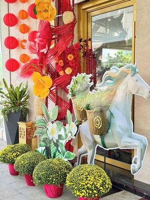 A decorative entrance with a white horse sculpture, red and yellow paper lanterns, and potted yellow flowers. - Sandals Stay Hotel (Hai Chau)