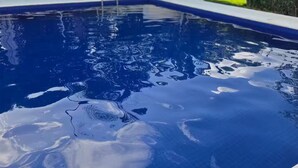 Et rektangulært swimmingpool med klart, blåt vand, omgivet af en hvid poolterrasse og en lav mur.