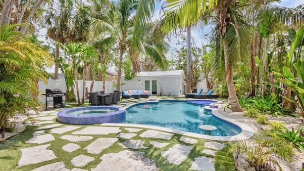 Un espace piscine comprenant un jacuzzi, des chaises longues et un petit bâtiment.