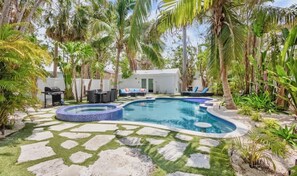 Un espace piscine comprenant un jacuzzi, des chaises longues et un petit bâtiment.