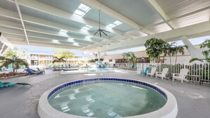 An indoor swimming pool with a circular design, surrounded by lounge chairs and a covered seating area.