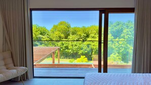 Un dormitorio con un gran ventanal corredera que da a una terraza exterior con una pérgola de madera.
