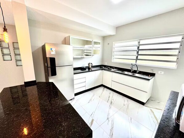 A modern kitchen with white cabinets, a black countertop, and a built-in stove.