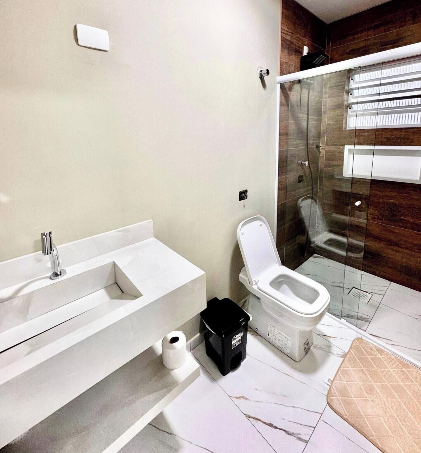 Et moderne badeværelse med bruser, toilet og håndvask.