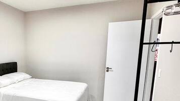 A bedroom with a bed, a wardrobe, and a mirror.