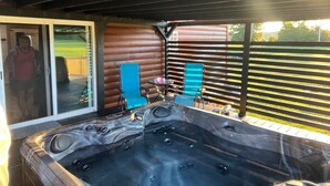 A hot tub with a glass door entrance, two blue chairs, and a small table.