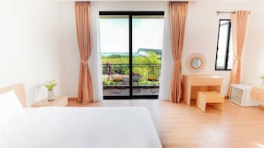 A hotel room with a large bed, a desk, a chair, and a view of a balcony with outdoor furniture. - Hometown An Vien Villa Hoi An (Hoi An)