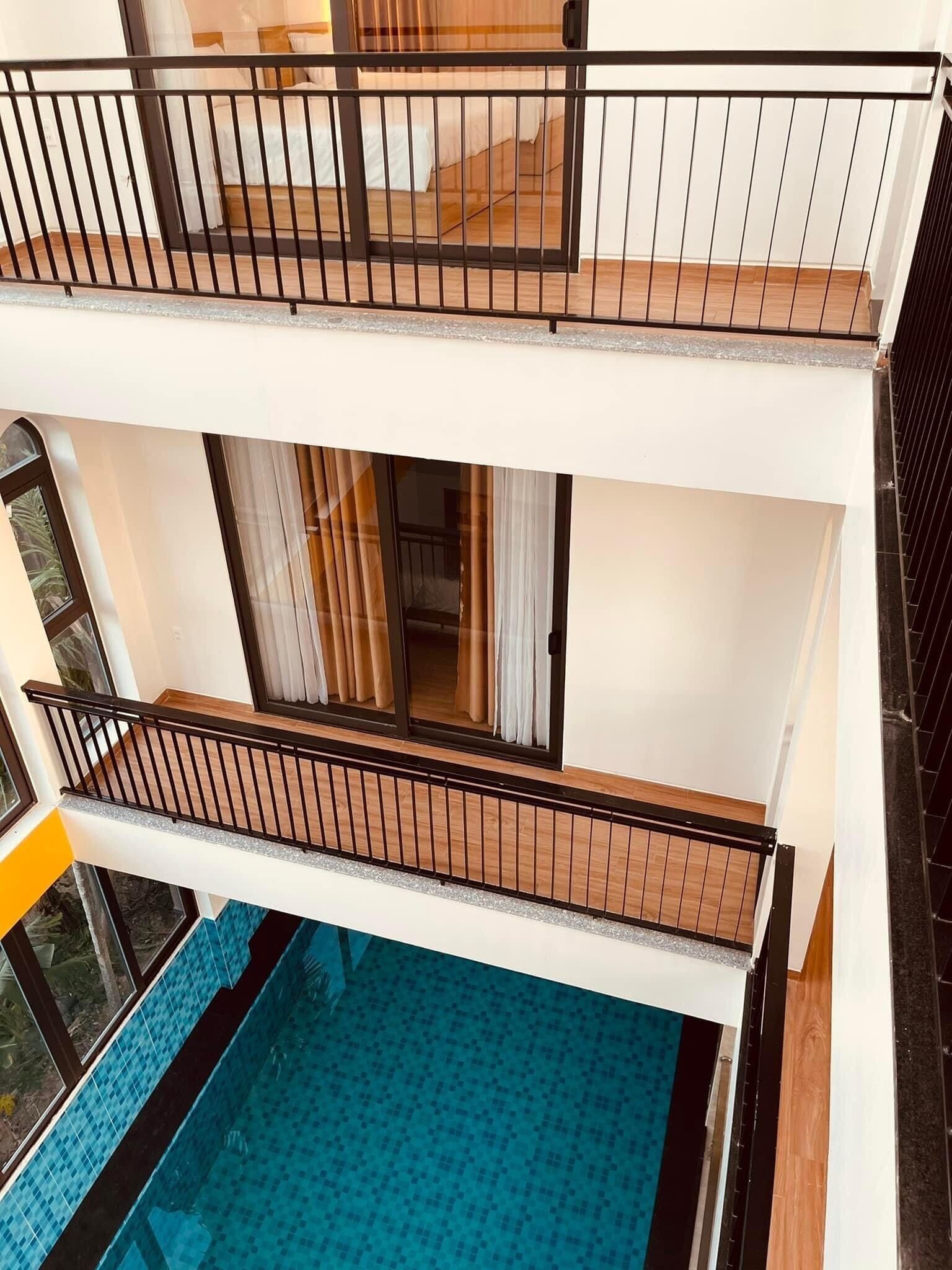 A multi-level residential building with balconies, a swimming pool, and large windows.