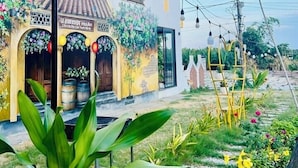 A multi-story hotel with balconies, a garden area with plants and flowers, and string lights. - Hometown An Vien Villa Hoi An (Hoi An)
