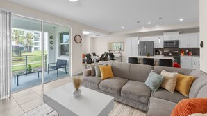 Un salon moderne avec un canapé gris, une table basse et un coin repas comprenant des chaises et une table.