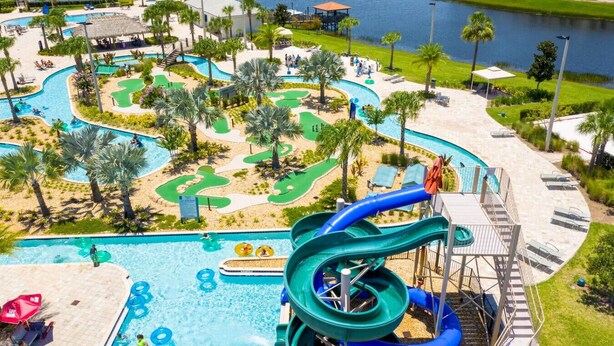 Un parc aquatique doté de nombreux toboggans et de plusieurs piscines, entouré de palmiers et bordé d’une étendue d’eau.