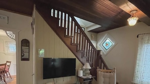 A living room with a wooden staircase, a flat-screen TV, a lamp, and a rocking chair. - Mount Gretna Magic ▪︎ 10 mins to Renaissance Faire  (Mount Gretna)