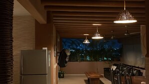 Eine Küche mit Kühlschrank, Holzbalkendecke und Pendelleuchten.