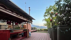 Eine Terrasse im Freien mit Holzdeck, einer roten Bar und Topfpflanzen.