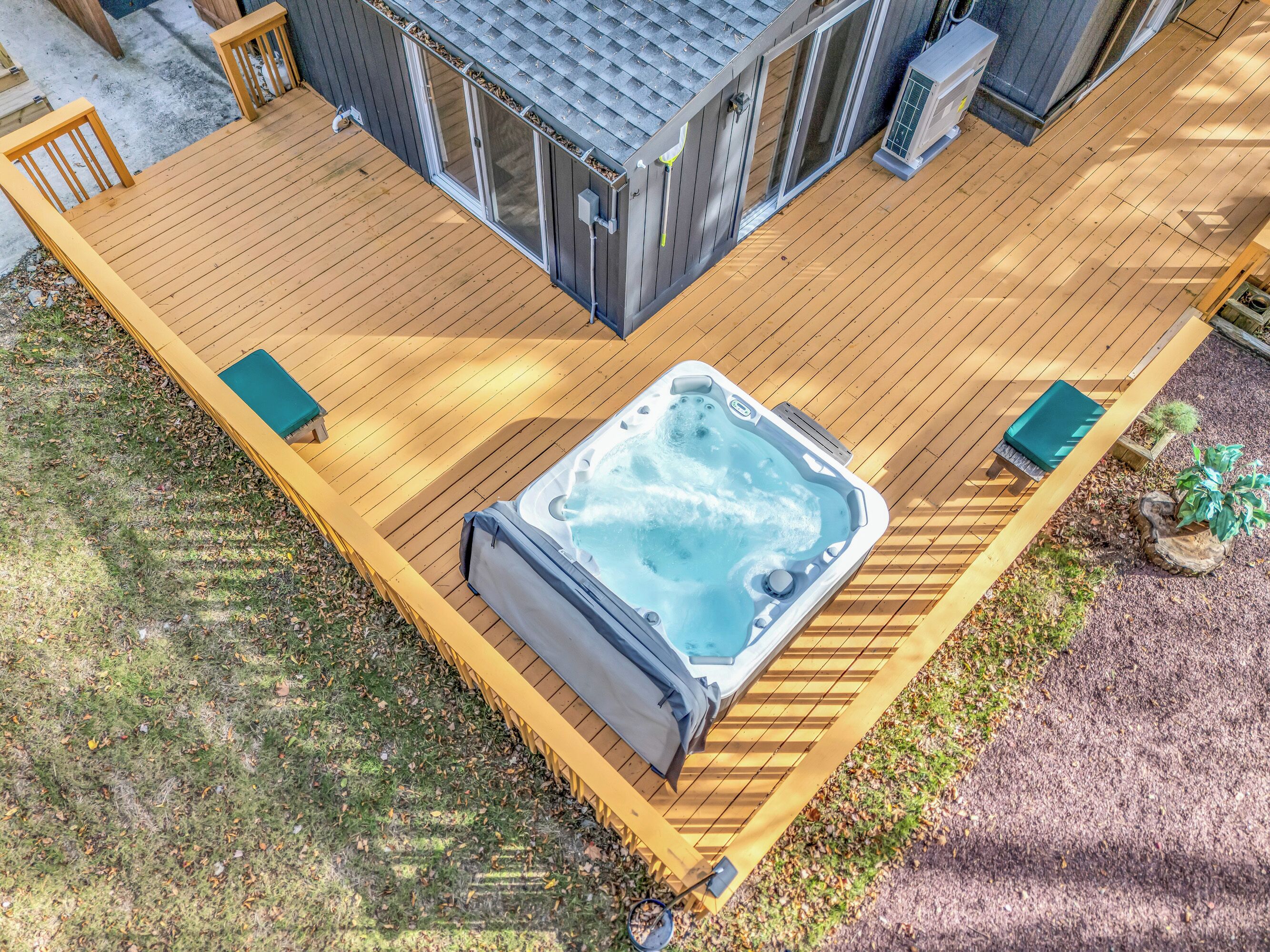 Ein Whirlpool auf einer Holzterrasse mit überdachter Sitzecke und einem kleinen Garten.