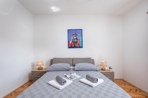 A bedroom with a bed, two bedside tables, a nightstand, a wall-mounted painting, and a patterned bedspread. - Holiday Home with Pool near Makarsk, Imotski, Croatia (Imotski)