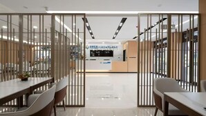 A modern hotel lobby with a reception desk, a large flat-screen TV, and a glass partition with vertical bars. - Qinhuangdao Beidaihe Yijing Hotel (Qinhuangdao)