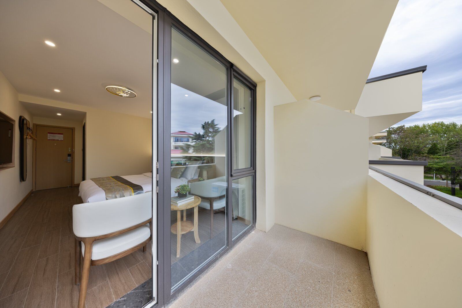 Habitación de hotel moderna con balcón, una cama, una mesita con una silla y vistas al exterior.
