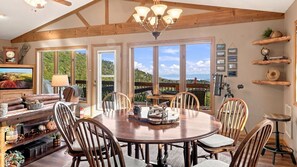 A dining area with a round table, chairs, and a view of the outdoors.