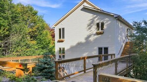 A two-story house with a wooden deck and a staircase leading to the upper level.