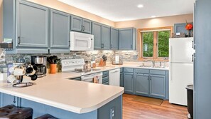 A modern kitchen with grey cabinets, a white microwave, and a built-in oven. - Long Range Views, Firepit, Hot tub, Game Room (Beech Mountain)